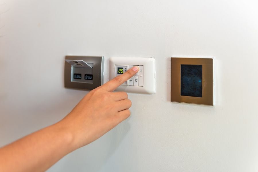 Image of someone pressing on a control panel attached to hvac system. Heat Pump Versus Furnace.