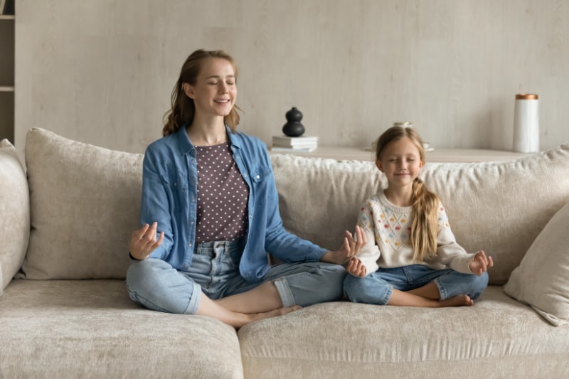 Air Conditioning Noise Concerns - Relaxed peaceful young mother and little daughter doing yoga exercises.