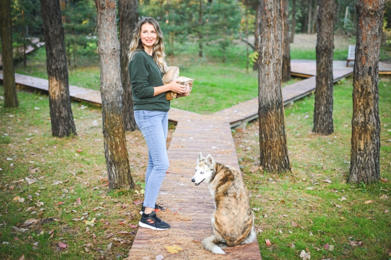 How Do I Know When It’s Time to Buy a New Furnace? Mature adult woman carrying firewood with a dog.