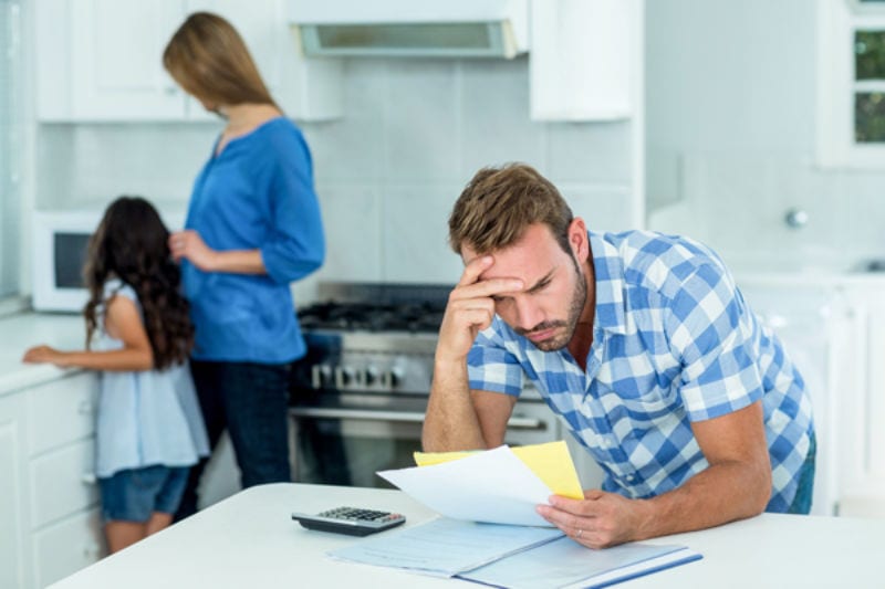 Worried father looking at bills at home