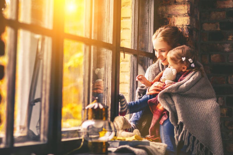 woman and child by window in blanket